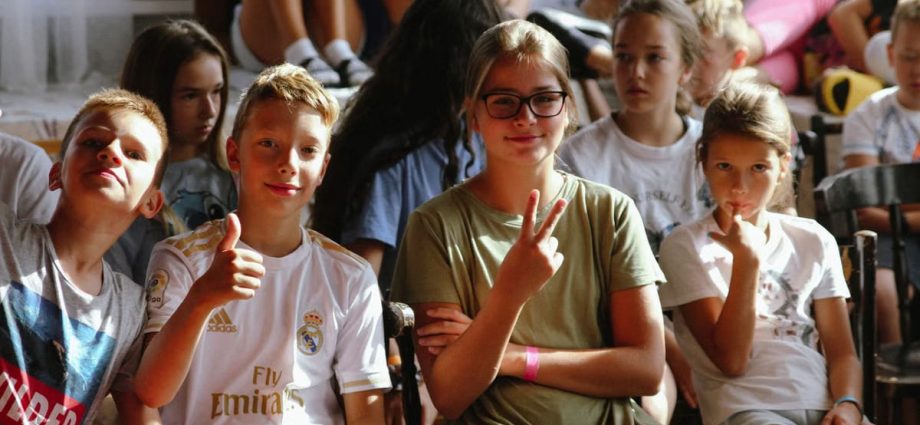 Cheerful group of children sitting together at an indoor event, showcasing friendships and diversity.